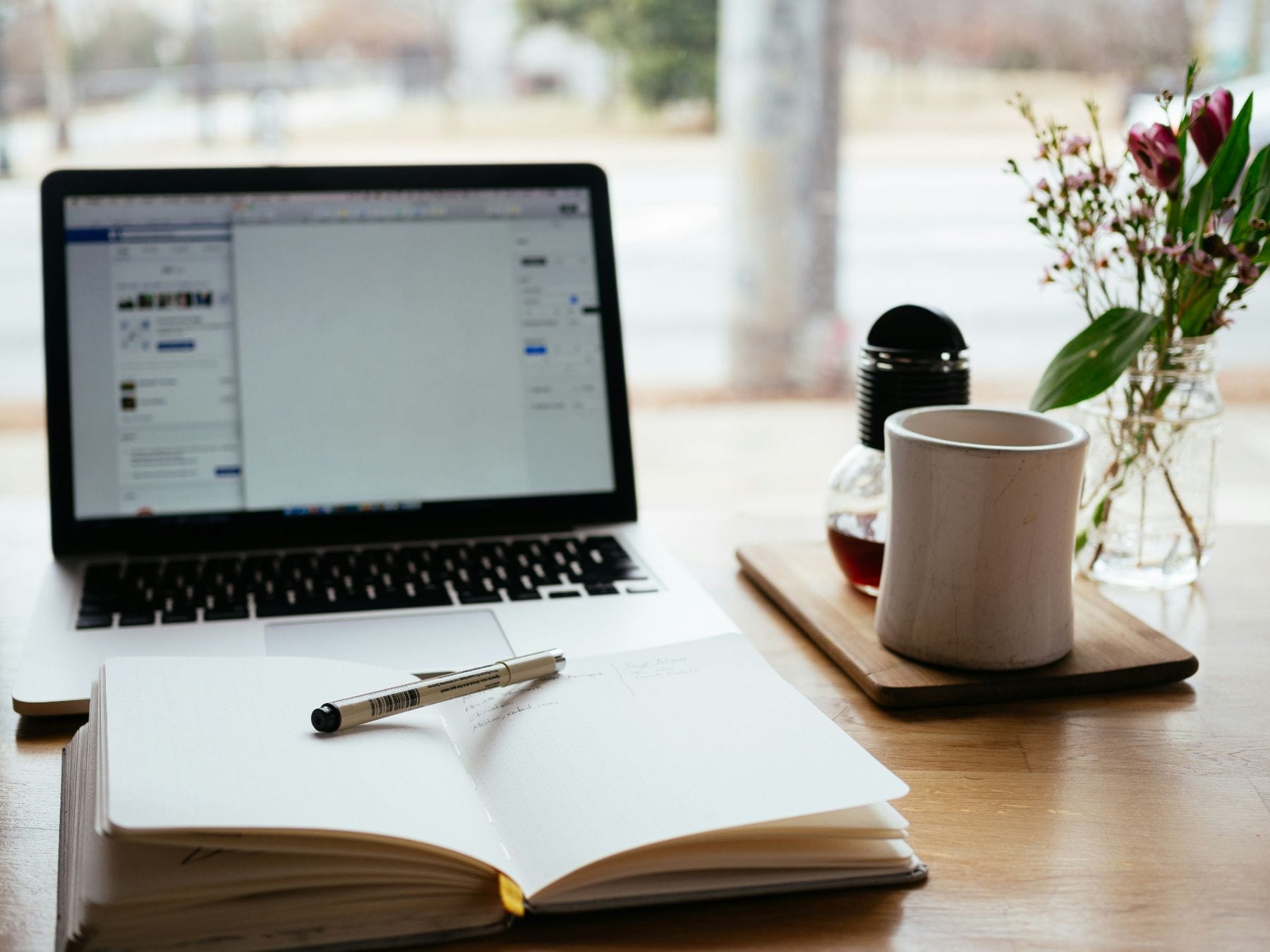 laptop met notitieboekje, pen en koffie